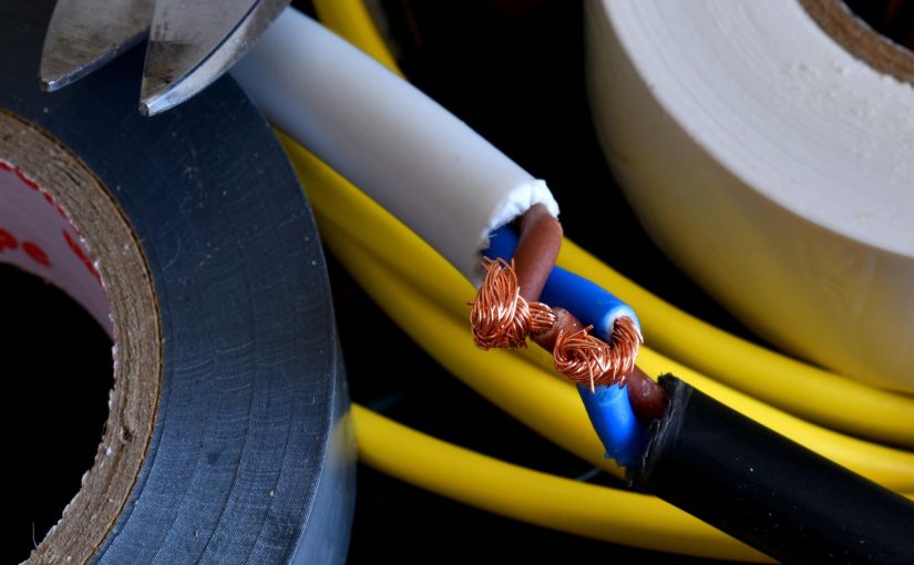 Przecięty kabel z widoczną miedzianą żyłą wyciągniętą z kolorowej izolacji.